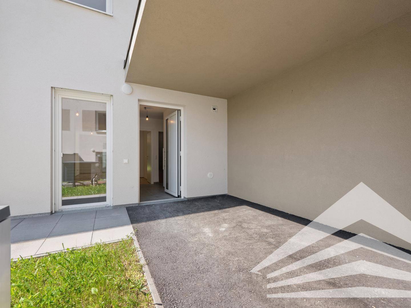 Überdachter Eingangsbereich mit gepflastertem Boden und Zugang zum Haus.