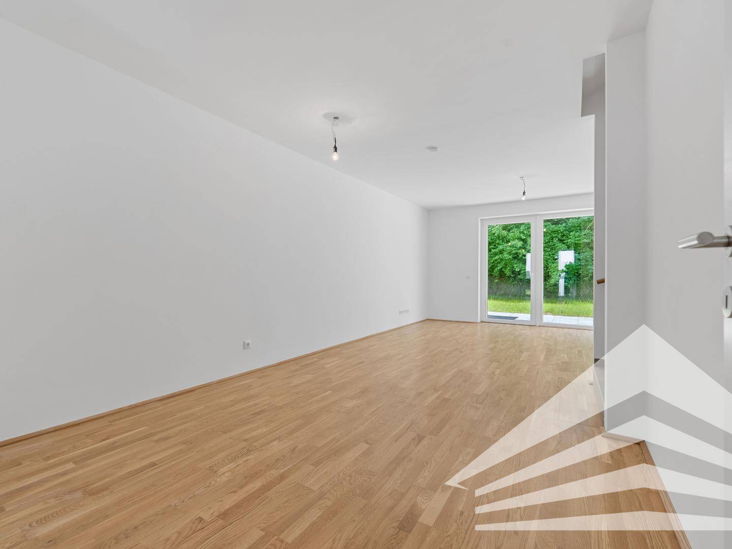 Geräumiges Wohnzimmer mit Parkettboden und großen Fenstern zum Garten.