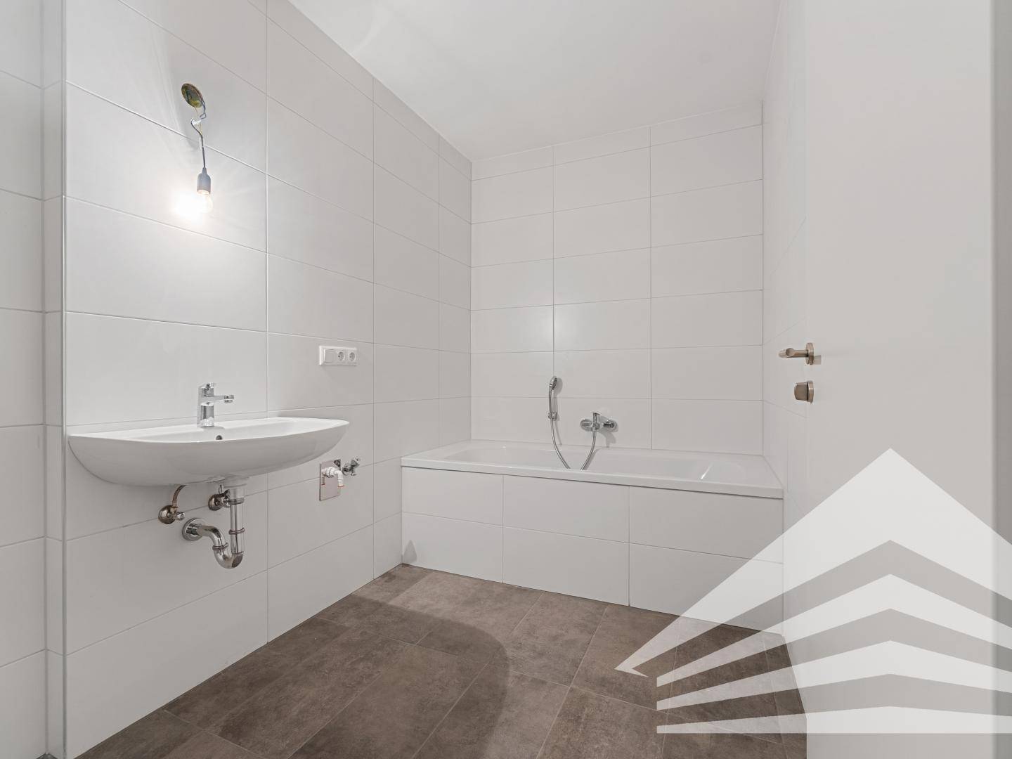 Modernes Badezimmer mit Badewanne, Waschbecken und weißen Wandfliesen.
