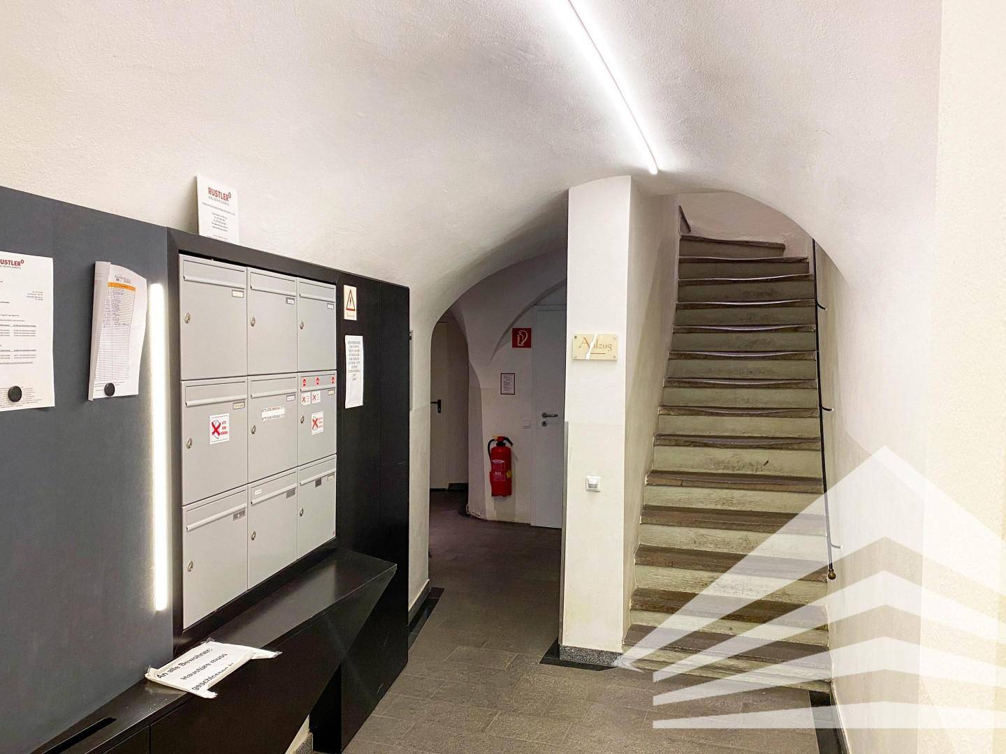 Eingangsbereich mit Briefkästen, gewölbter Decke und Treppenaufgang in einem historischen Gebäude.