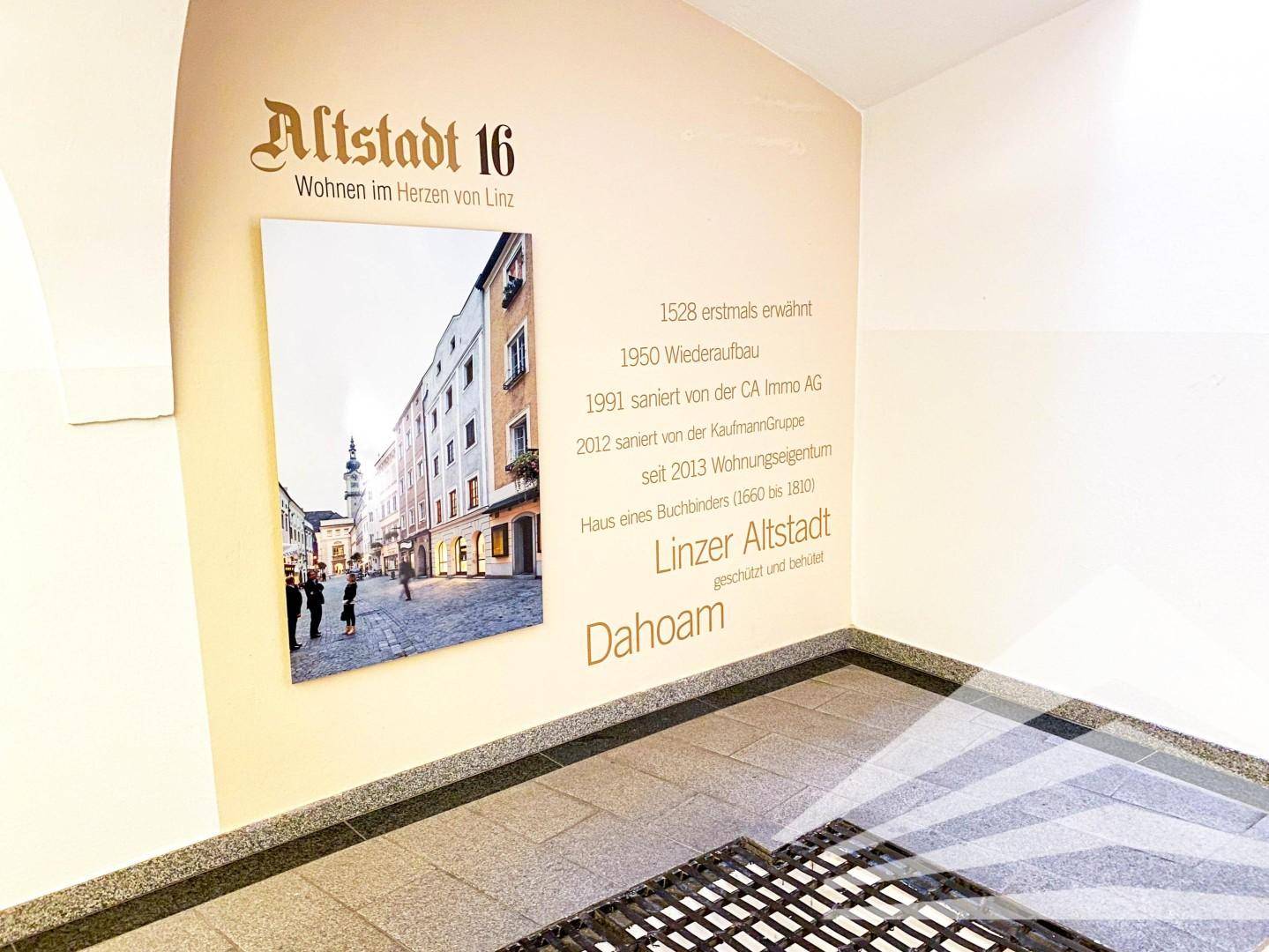 Eingangsbereich mit historischer Informationstafel und Bild der Altstadt, die die Geschichte des Gebäudes hervorhebt.