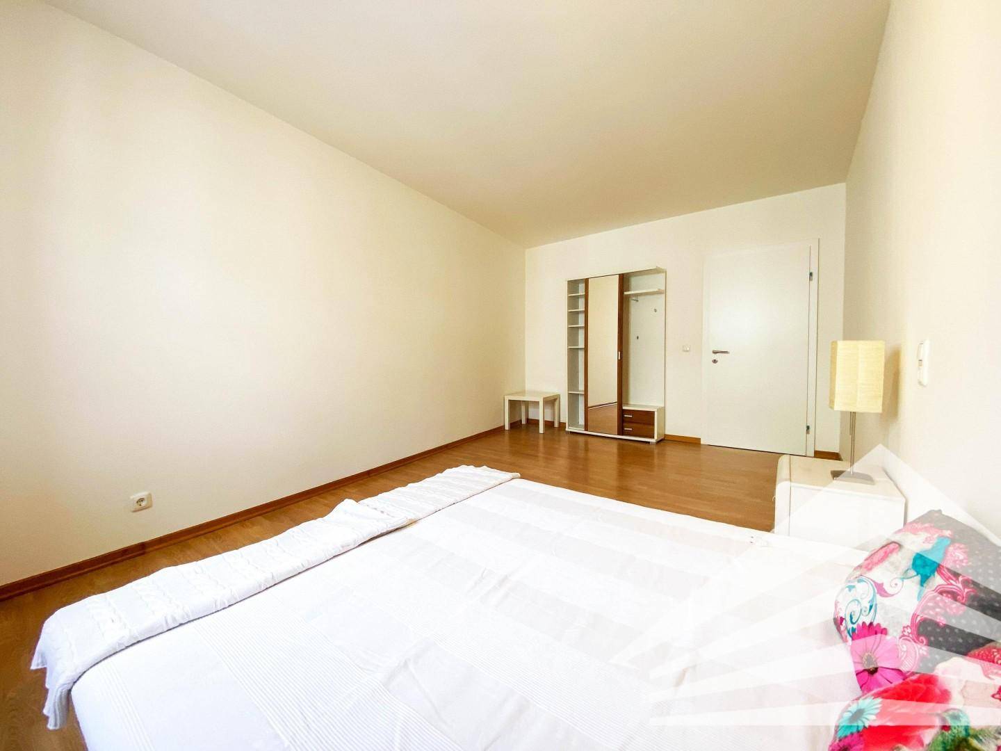 Geräumiges Schlafzimmer mit Holzboden und offenem Kleiderschrank, bietet viel Stauraum.