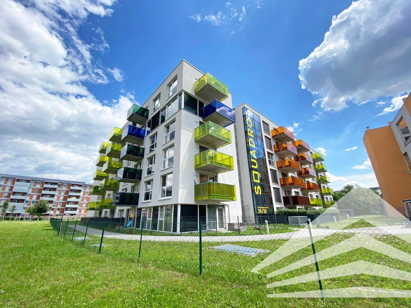 Moderne Wohnanlage mit farbenfrohen Balkonen und einer ansprechenden Architektur unter blauem Himmel.