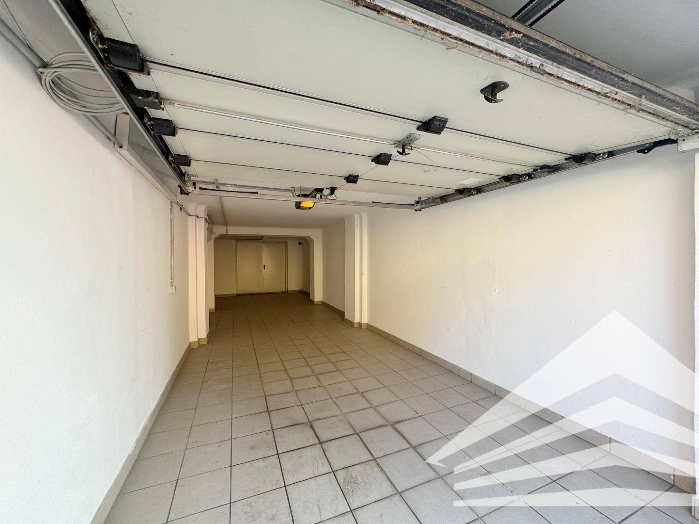 Geräumiger Garagenplatz mit Fliesenboden und automatischem Toröffner, ideal für ein Fahrzeug.