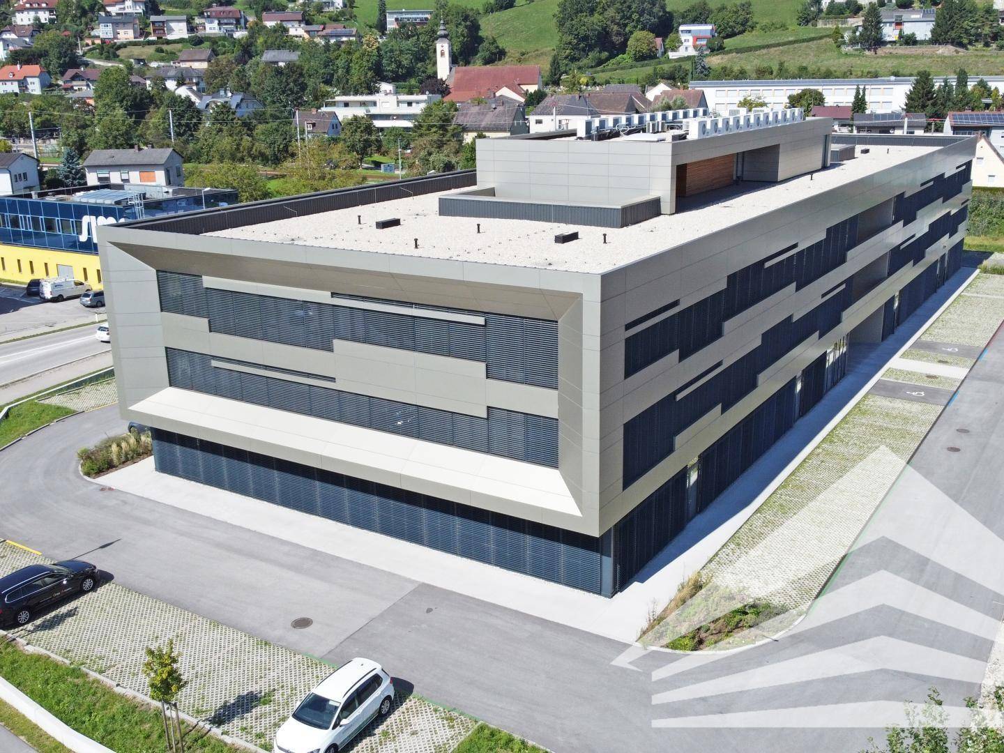 Vogelperspektive des modernen Bürokomplexes mit Parkplätzen und der umliegenden Bebauung.