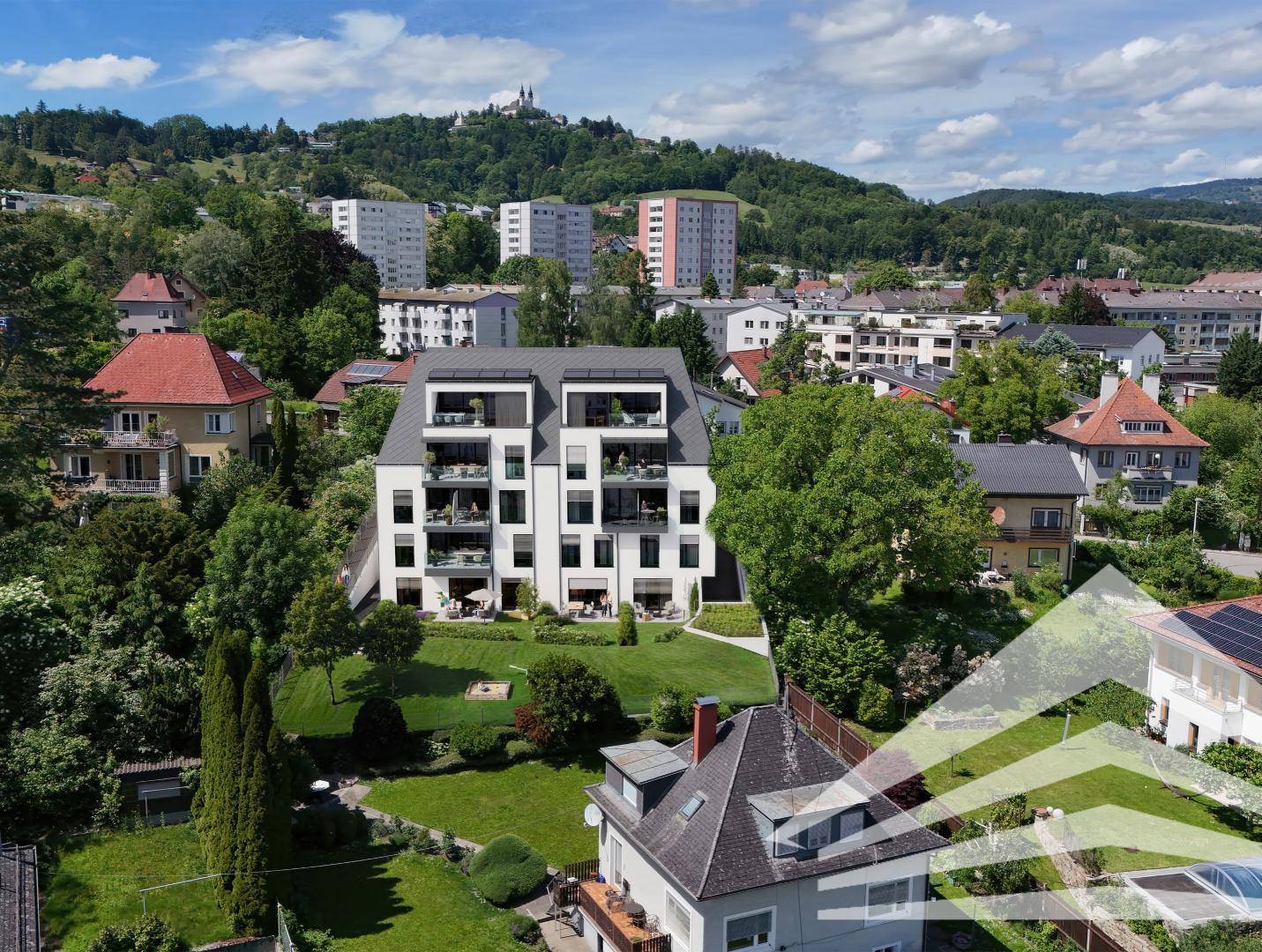 Luftaufnahme der modernen Wohnanlage in einer grünen Wohngegend mit Stadt- und Bergblick.