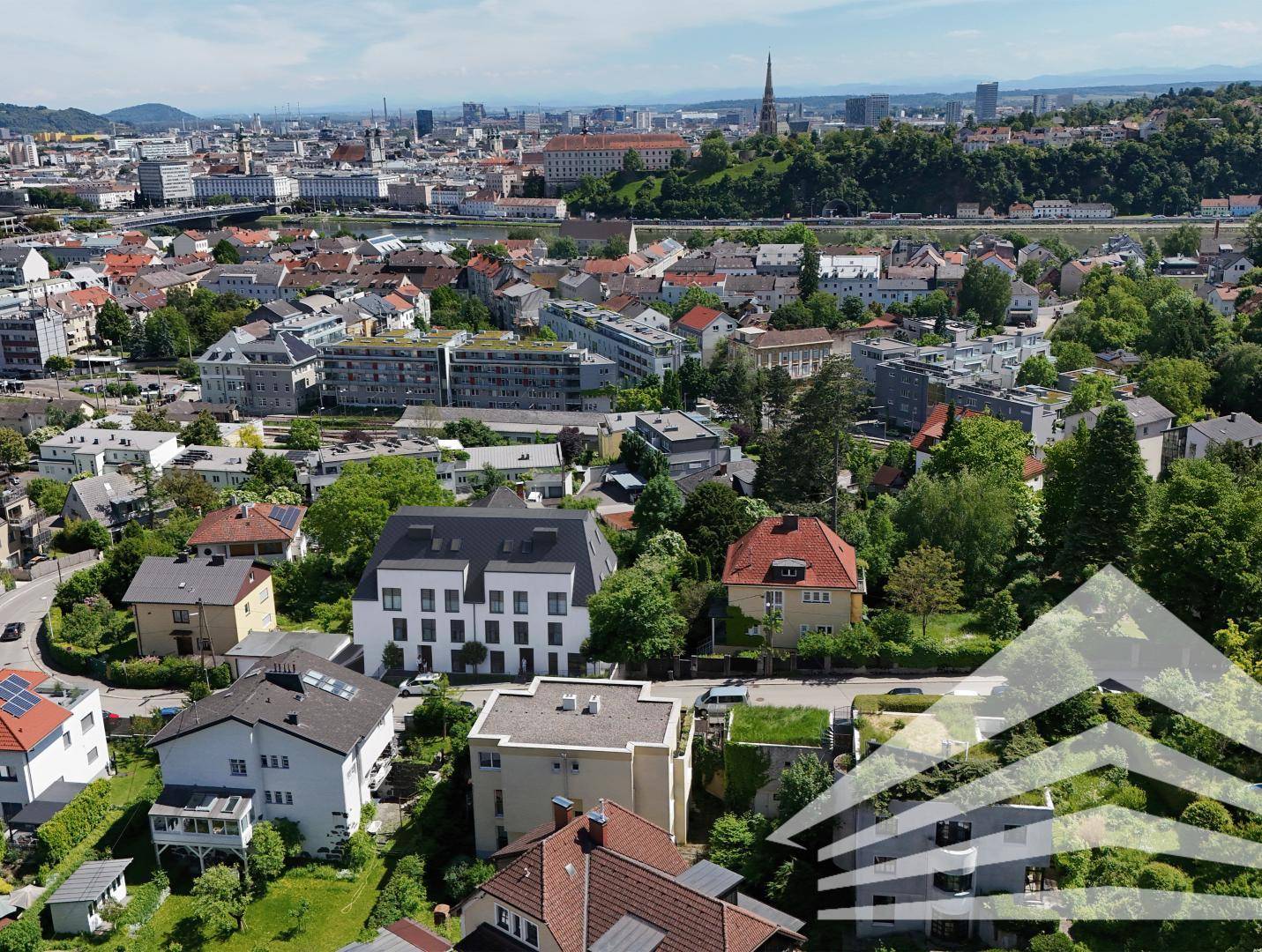 Weitläufige Luftaufnahme der Stadt mit dem modernen Gebäude, Fluss und Bergen im Hintergrund.
