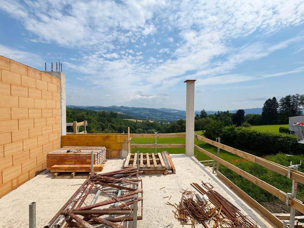 Baustelle mit Rohbau und weitem Blick über die grüne Hügellandschaft.