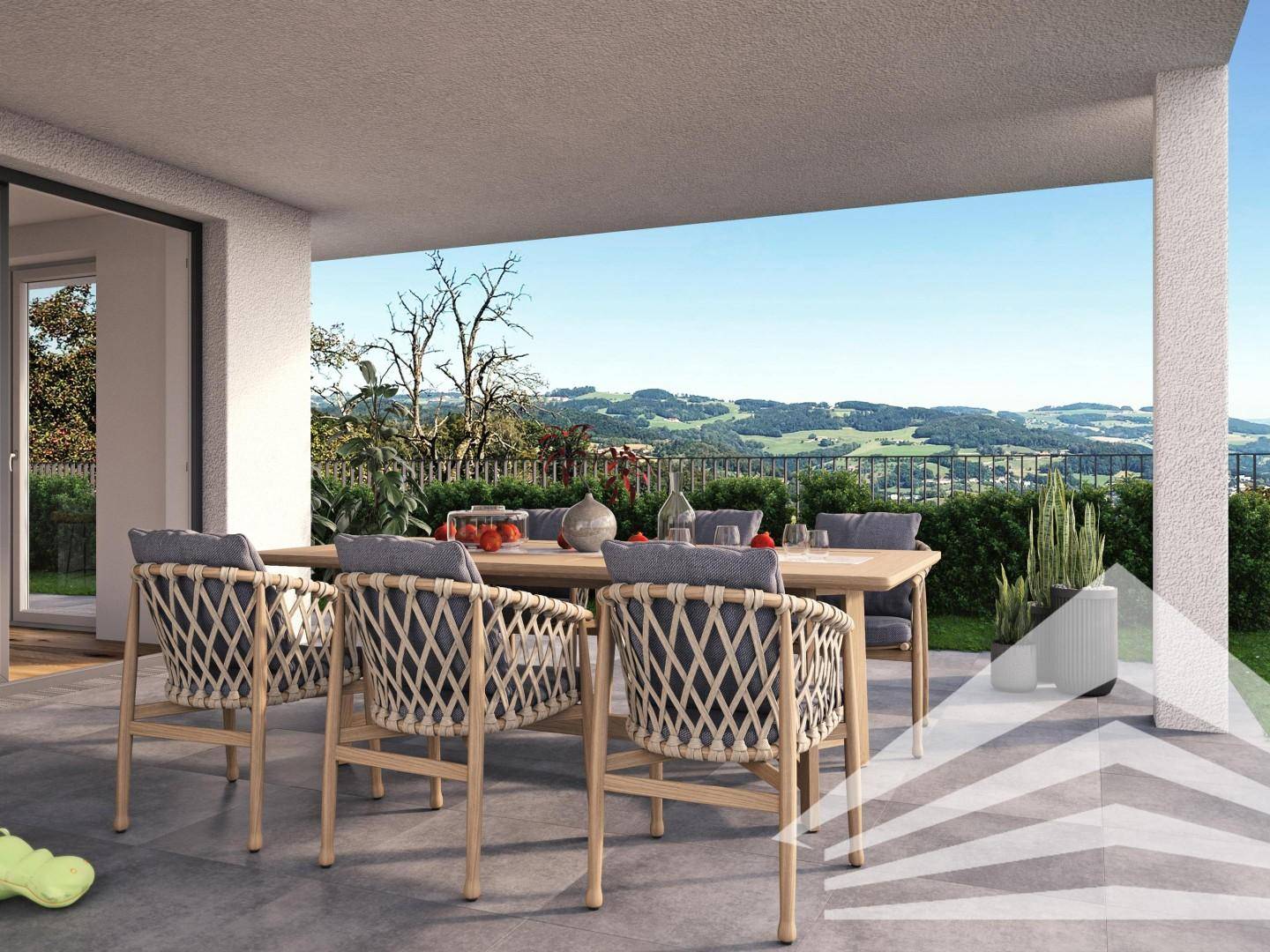 Große Terrasse mit Esstisch und Stühlen, bietet einen weiten Blick über die grüne Landschaft.