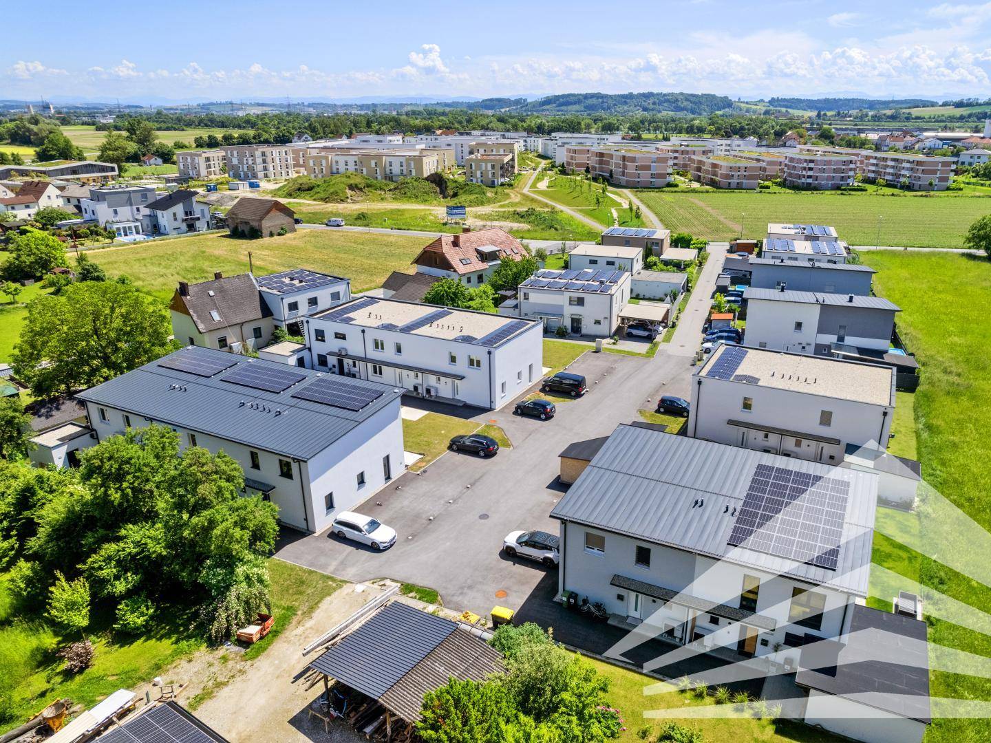Weitläufige Wohnsiedlung mit modernen Häusern, umgeben von grünen Feldern und Natur.