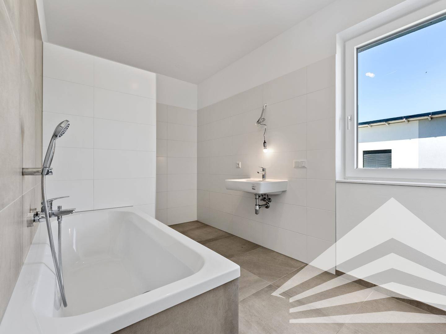 Modernes Badezimmer mit Badewanne, Waschbecken und großem Fenster.