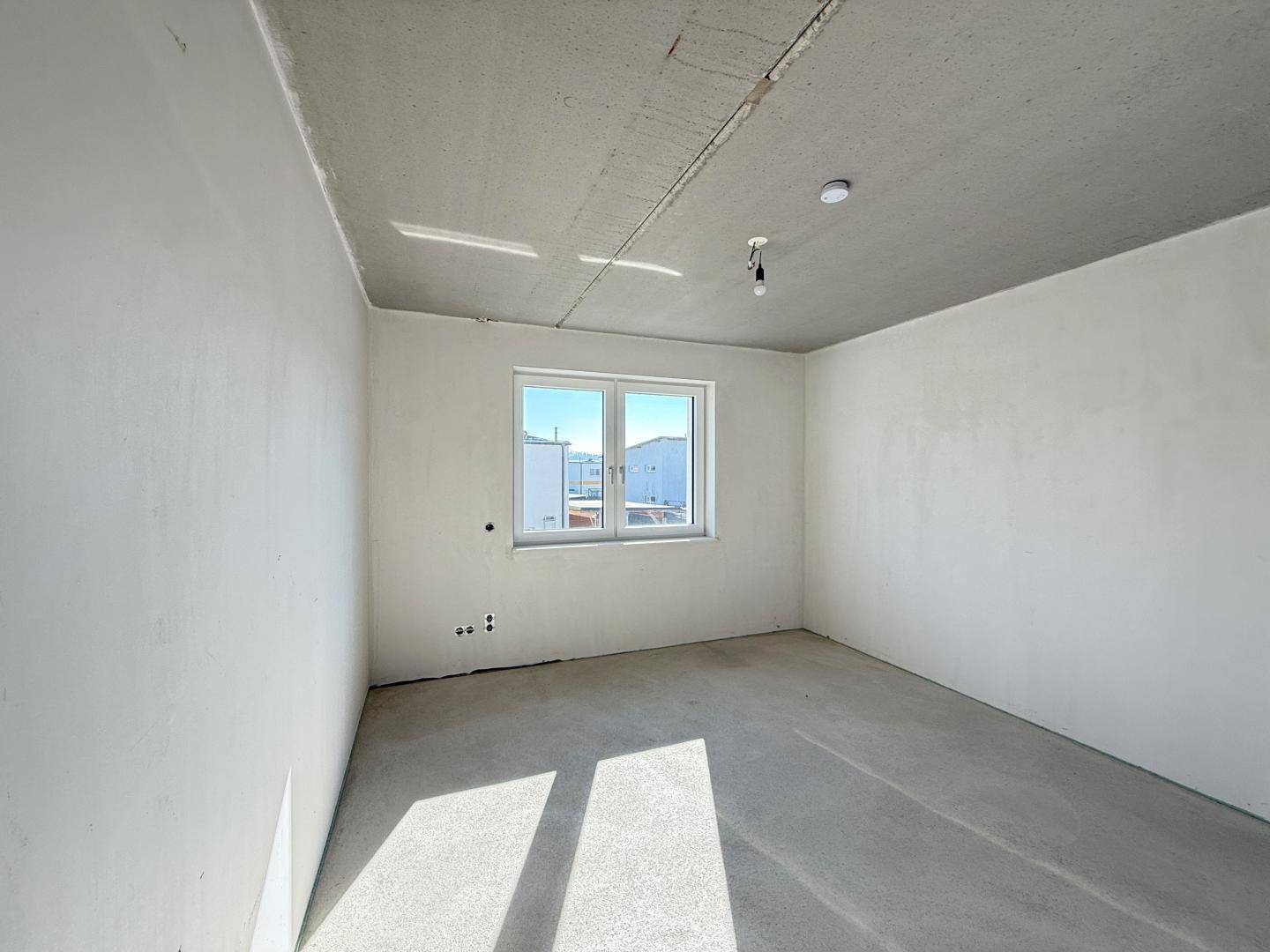 Unfertiges Zimmer mit einem Fenster, das den Raum mit natürlichem Licht füllt.