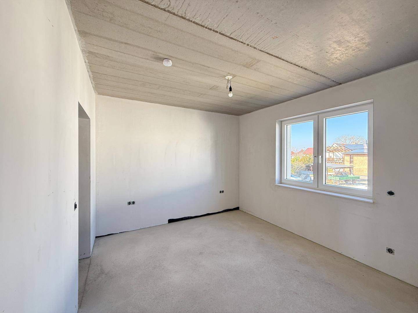 Helles, unfertiges Zimmer mit Blick auf die umliegenden Häuser und Gärten.