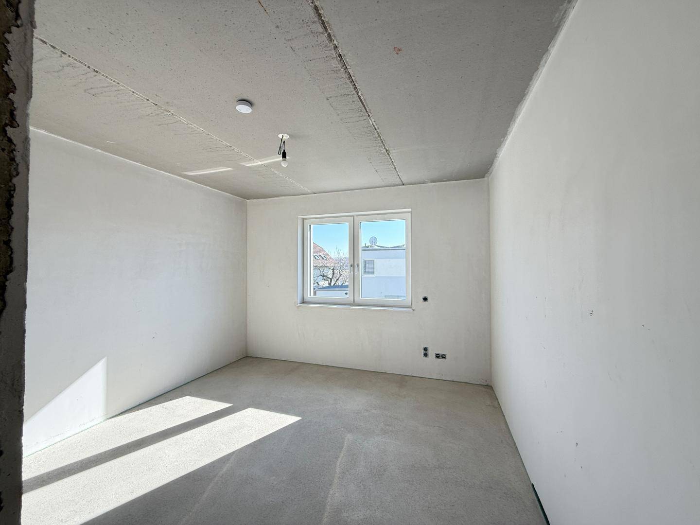 Unfertiges Zimmer mit einem Fenster, das viel Tageslicht hereinlässt.