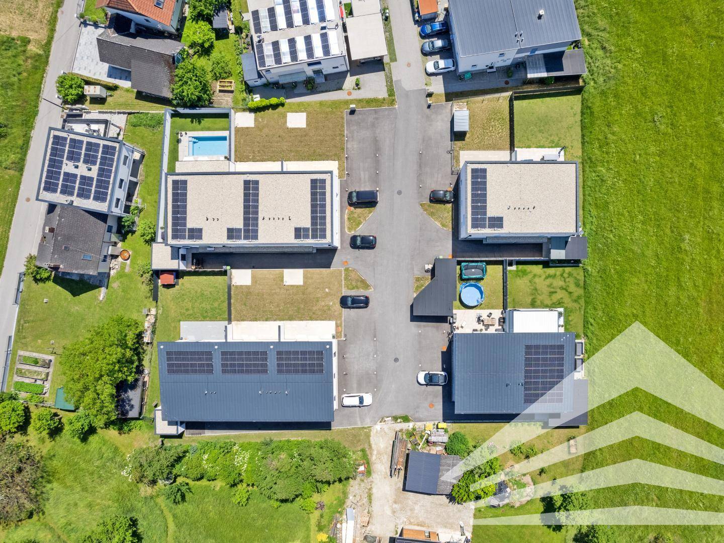 Vogelperspektive einer Wohnsiedlung mit modernen Häusern und Solaranlagen auf den Dächern.