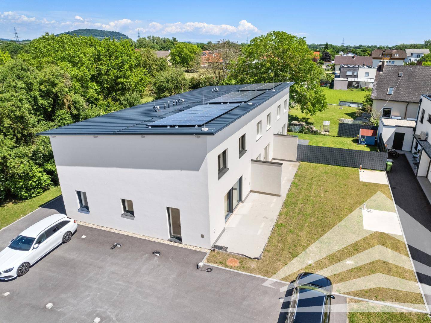 Moderne Doppelhaushälfte mit Flachdach, Solaranlage und kleinem Garten.