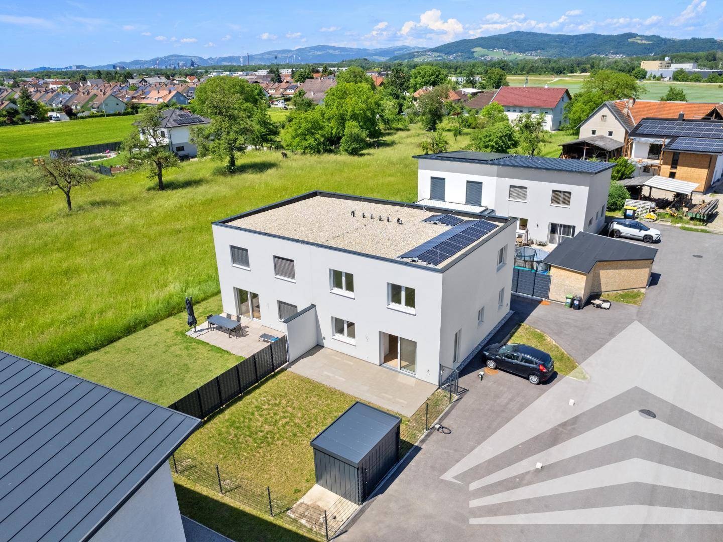 Moderne Doppelhaushälfte mit Garten, Terrasse und Solaranlage auf dem Dach.