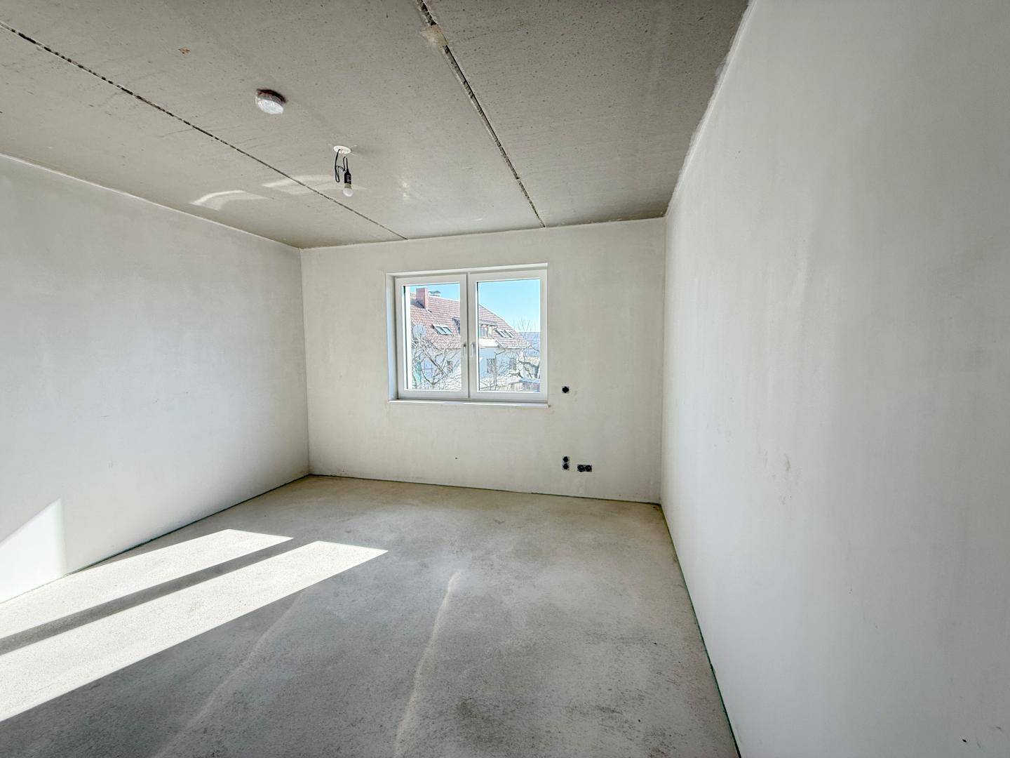 Unfertiger Raum mit Fenster und Blick auf die Umgebung, bereit für den Ausbau.