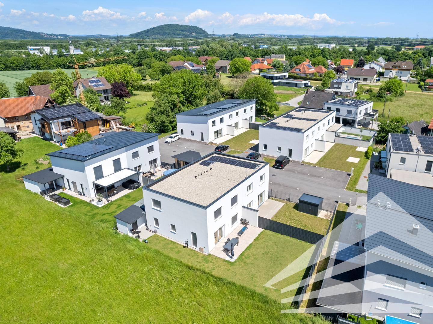 Luftaufnahme einer modernen Wohnsiedlung mit viel Grün und Bergblick.