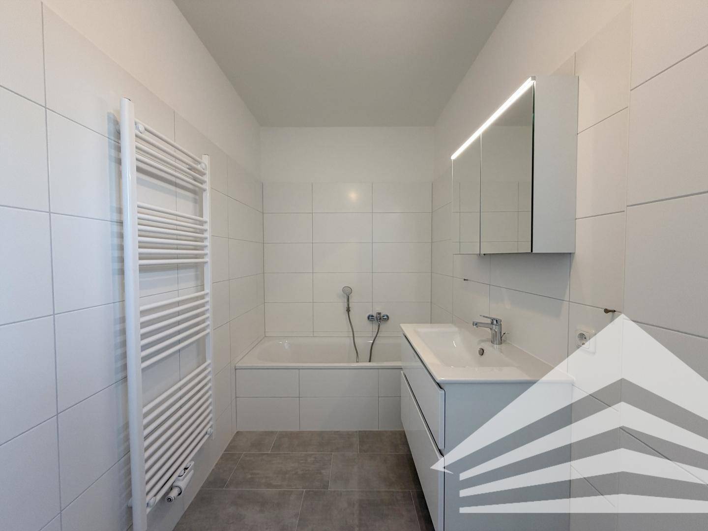 Modernes Badezimmer mit Badewanne, Waschtisch und beheiztem Handtuchhalter.