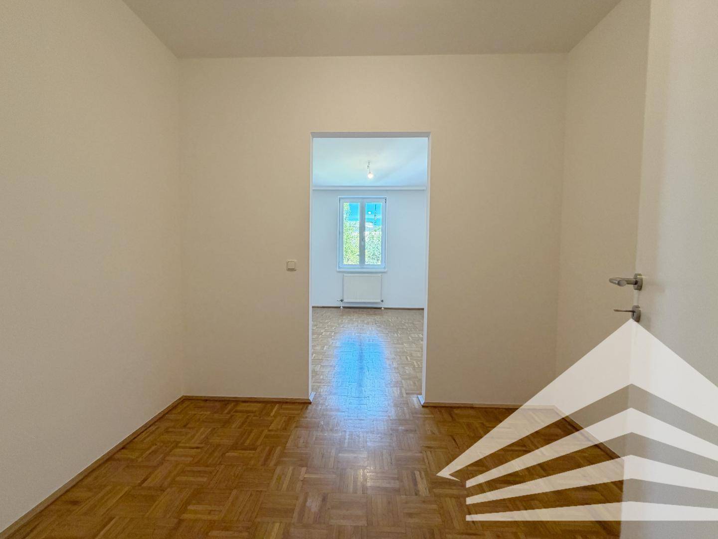 Heller Flur mit Parkettboden und Durchgang zu einem weiteren Zimmer.