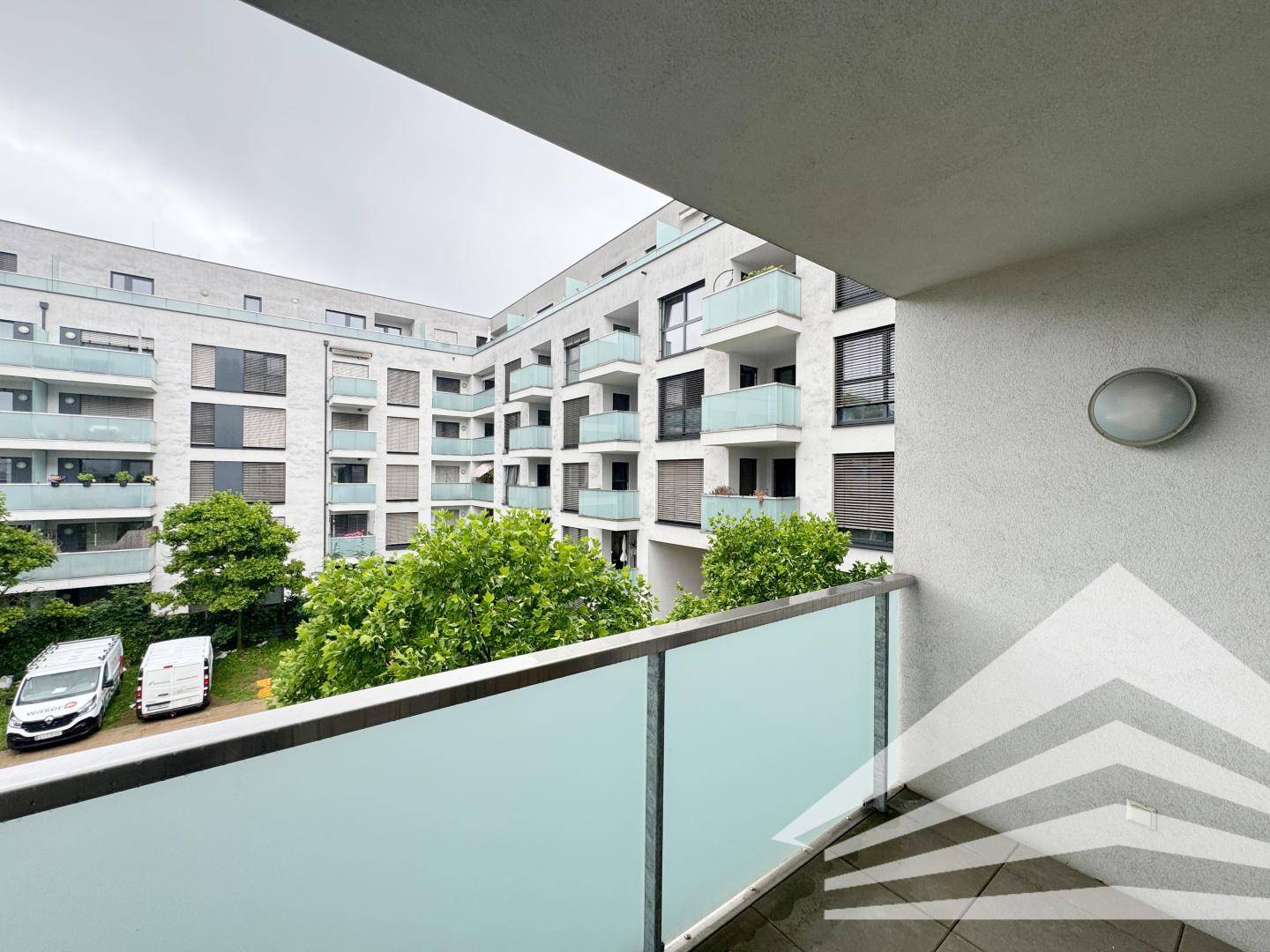 Geräumiger Balkon mit weitem Blick auf den modernen Innenhof und die Wohnanlage.