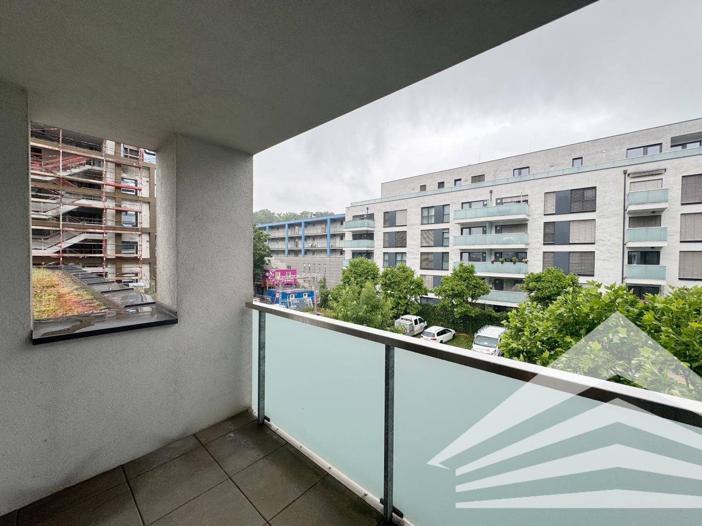 Balkon mit Blick auf einen begrünten Innenhof und umliegende Wohngebäude.