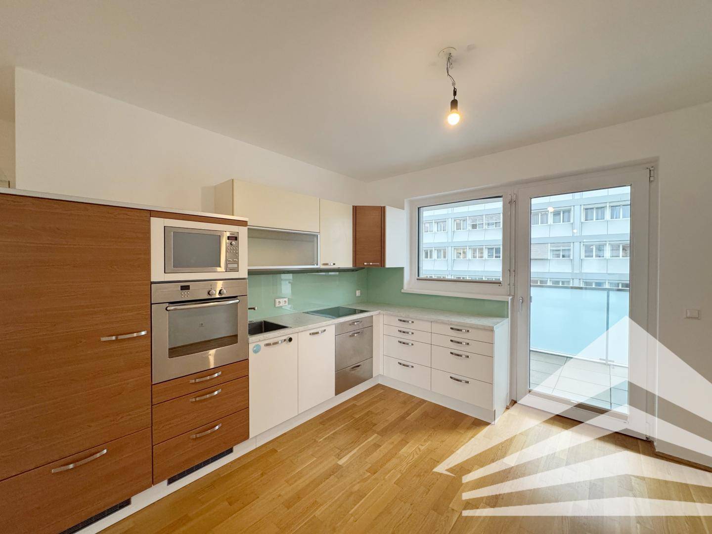 Moderne Einbauküche mit hellen Fronten, Holzdetails und integrierten Geräten, mit Balkonzugang.