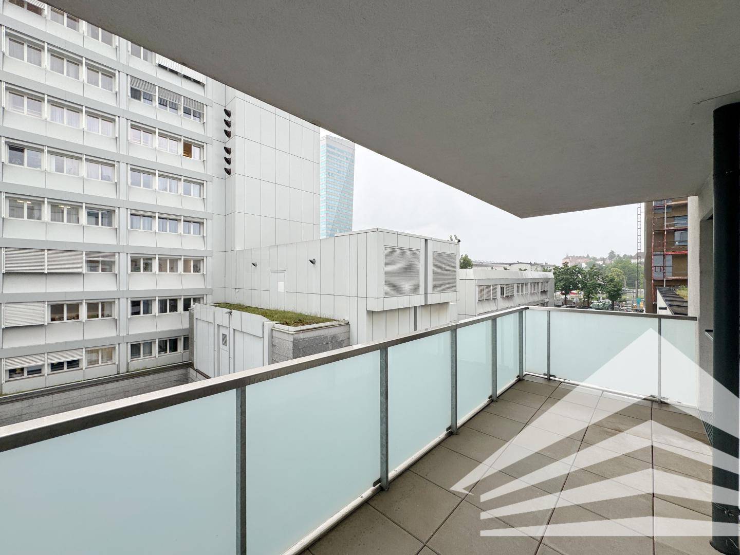 Geräumiger Balkon mit Blick auf die umliegenden Gebäude und eine begrünte Dachfläche.