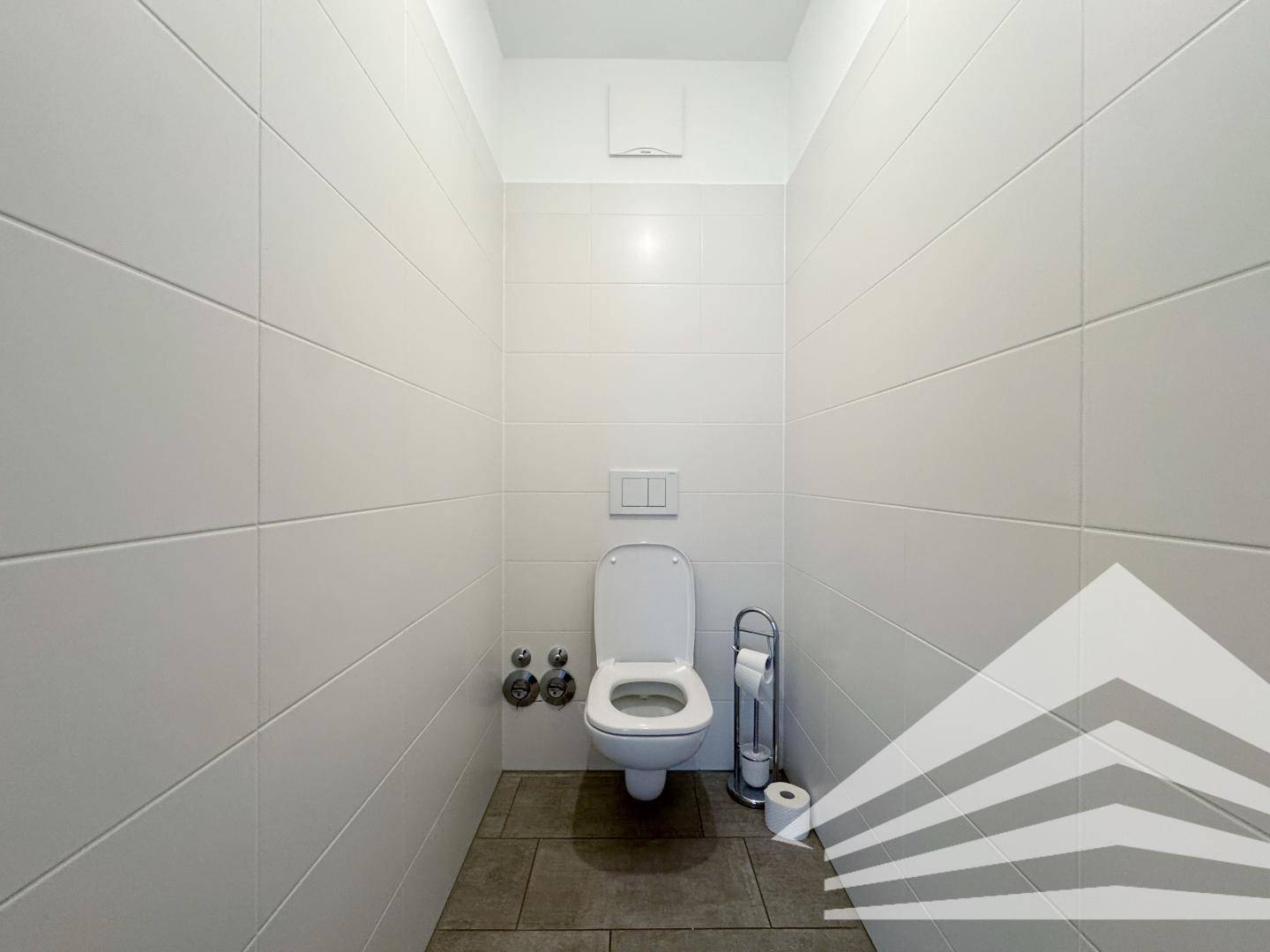 Separates WC mit modernen Fliesen und wandhängender Toilette.