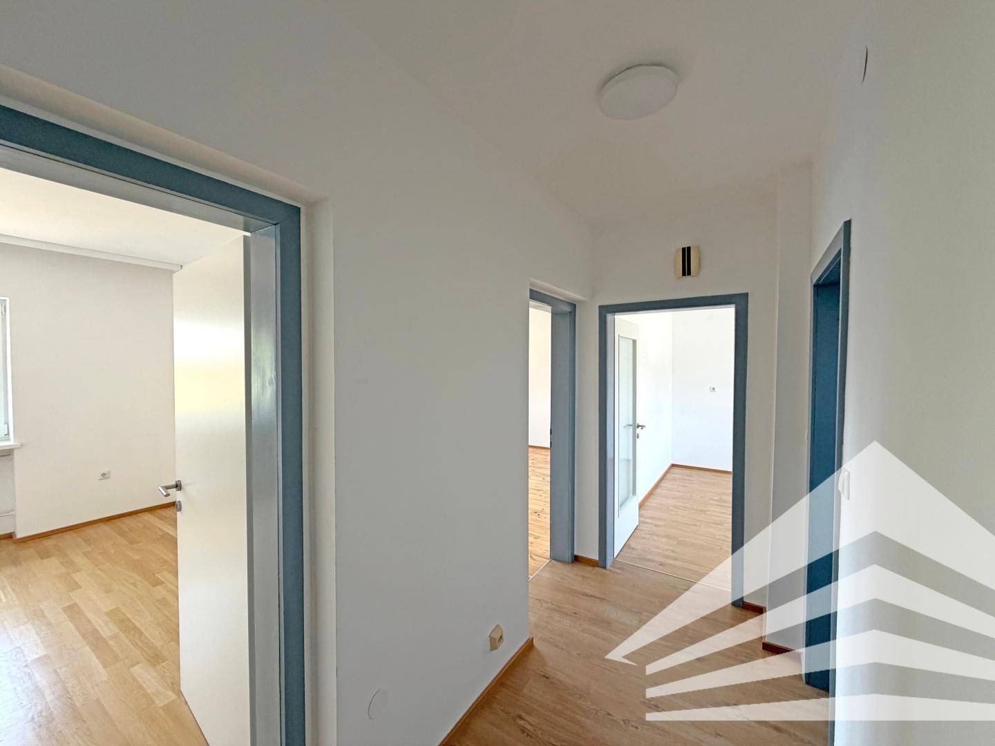 Heller Flur mit Laminatboden und mehreren offenen Türen, die zu den angrenzenden Zimmern führen.