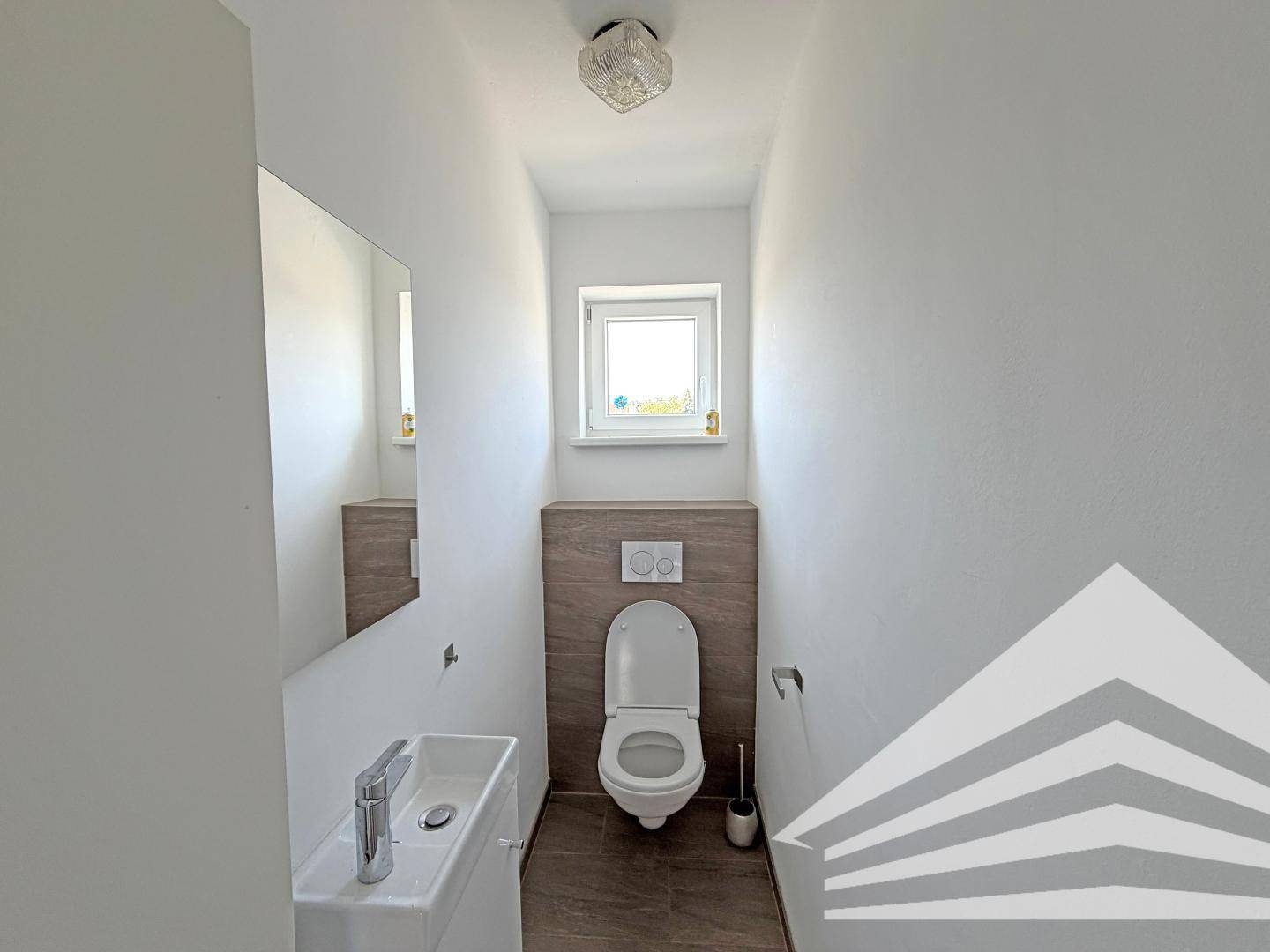 Modernes Gäste-WC mit wandhängendem WC, kleinem Waschbecken und einem Fenster für Tageslicht.