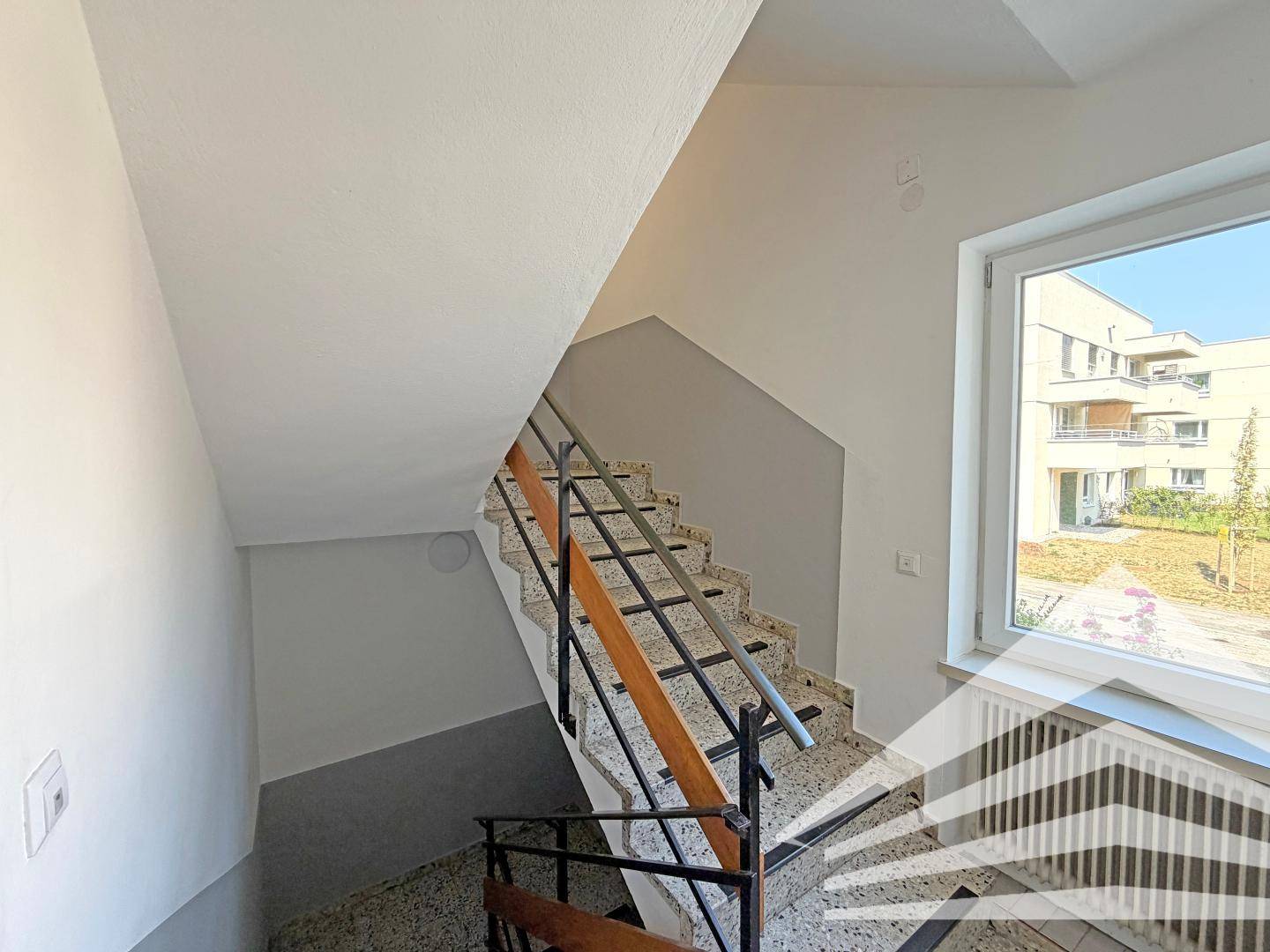 Treppenhaus mit Terrazzoboden und Metallgeländer, das die verschiedenen Etagen verbindet.