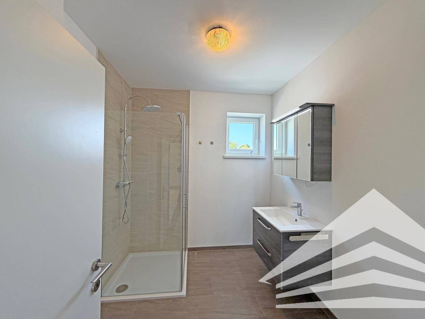 Modernes Badezimmer mit Duschkabine, Fliesenboden und einem Fenster für natürliche Belüftung.