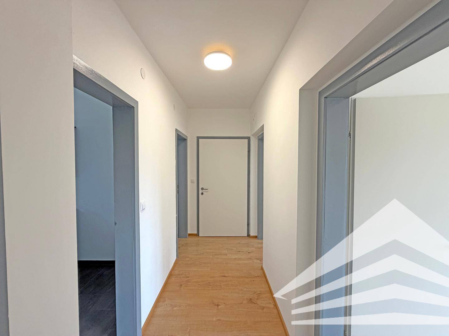 Heller Flur mit Laminatboden und mehreren Türen, die zu den angrenzenden Zimmern führen.