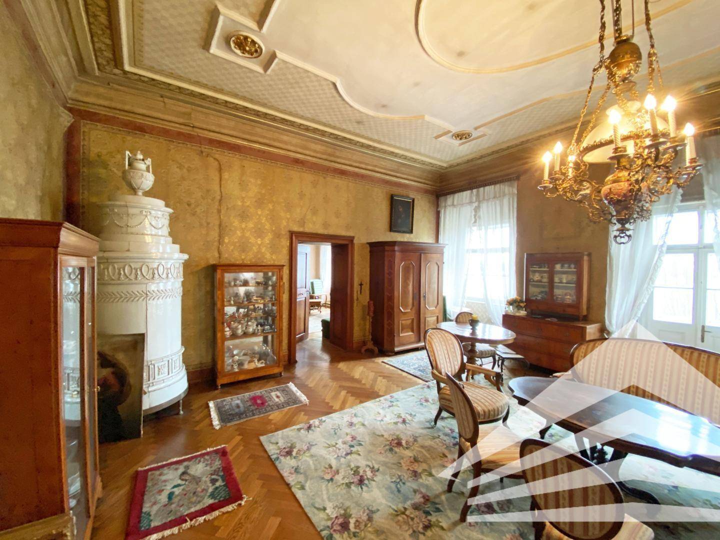 Prunkvolles Wohnzimmer mit Kachelofen, Parkettboden und opulentem Kronleuchter.