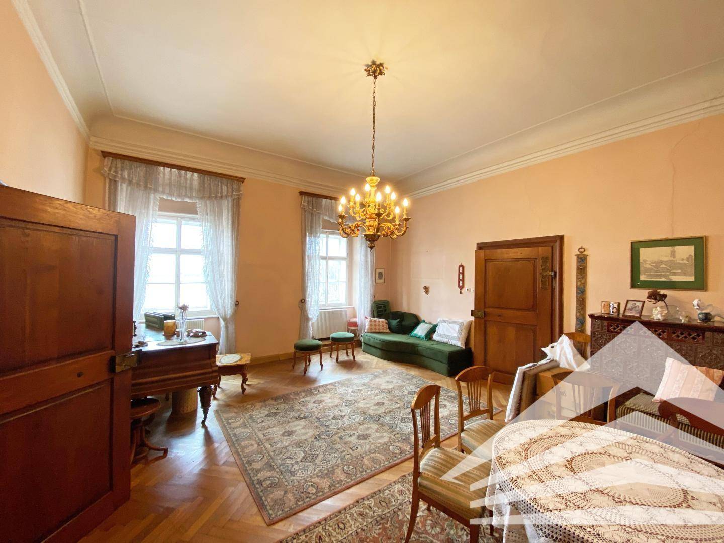 Großes Wohnzimmer mit Parkettboden, antiken Möbeln und einem Kronleuchter.