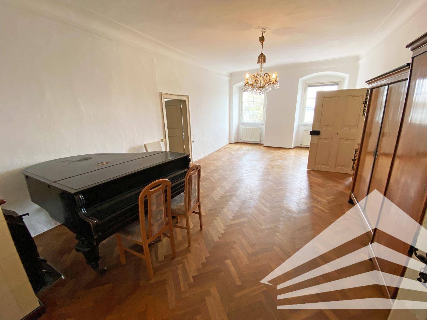 Elegantes Wohnzimmer mit Flügel, Parkettboden und Kronleuchter, das viel Platz bietet.