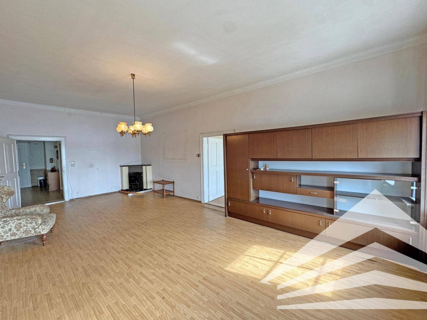Wohnzimmer mit Laminatboden, einem Kamin und einem großen Wandschrank.