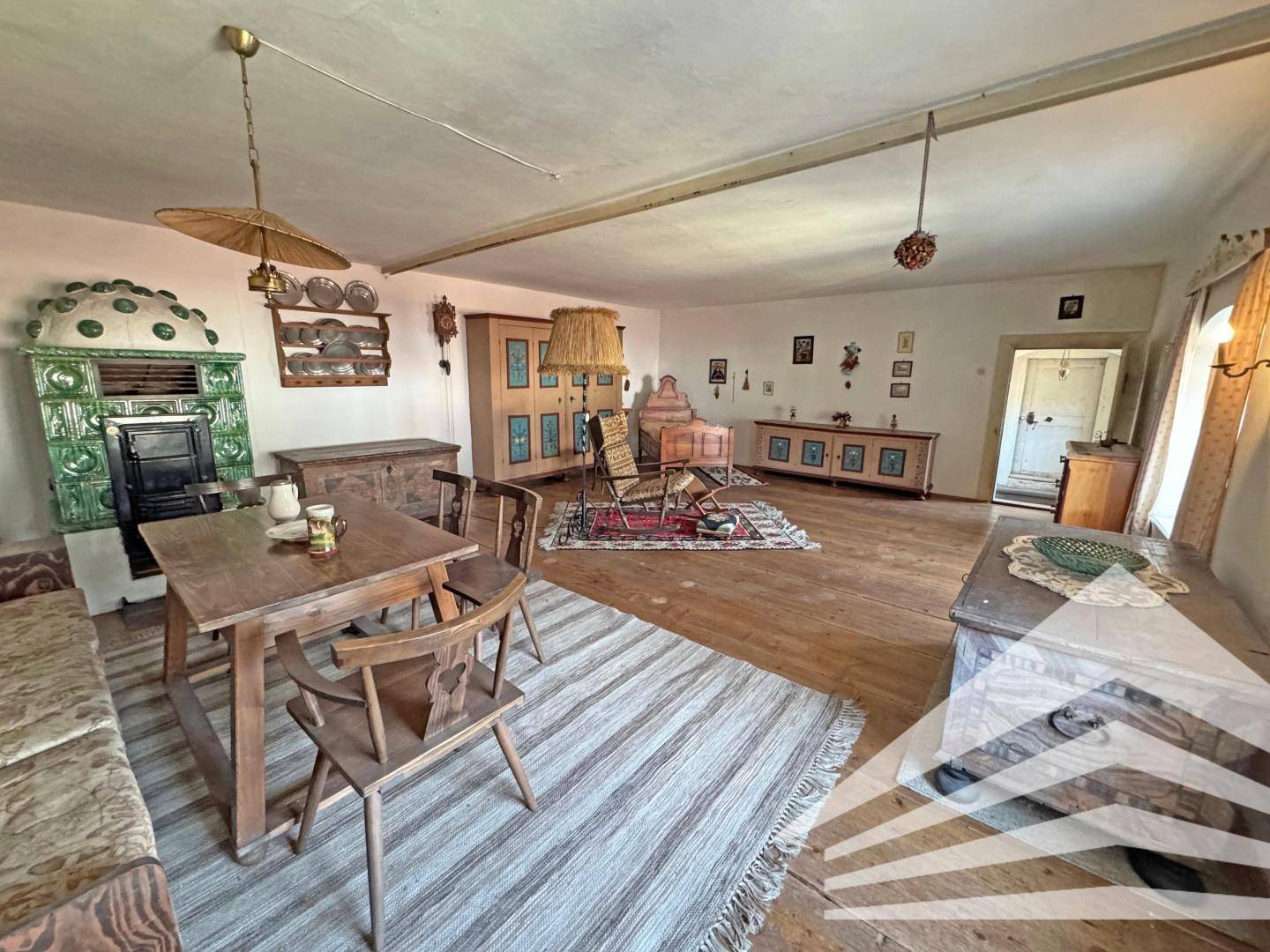 Gemütliches Wohnzimmer im traditionellen Stil mit Holzboden, Kachelofen und rustikalen Möbeln.