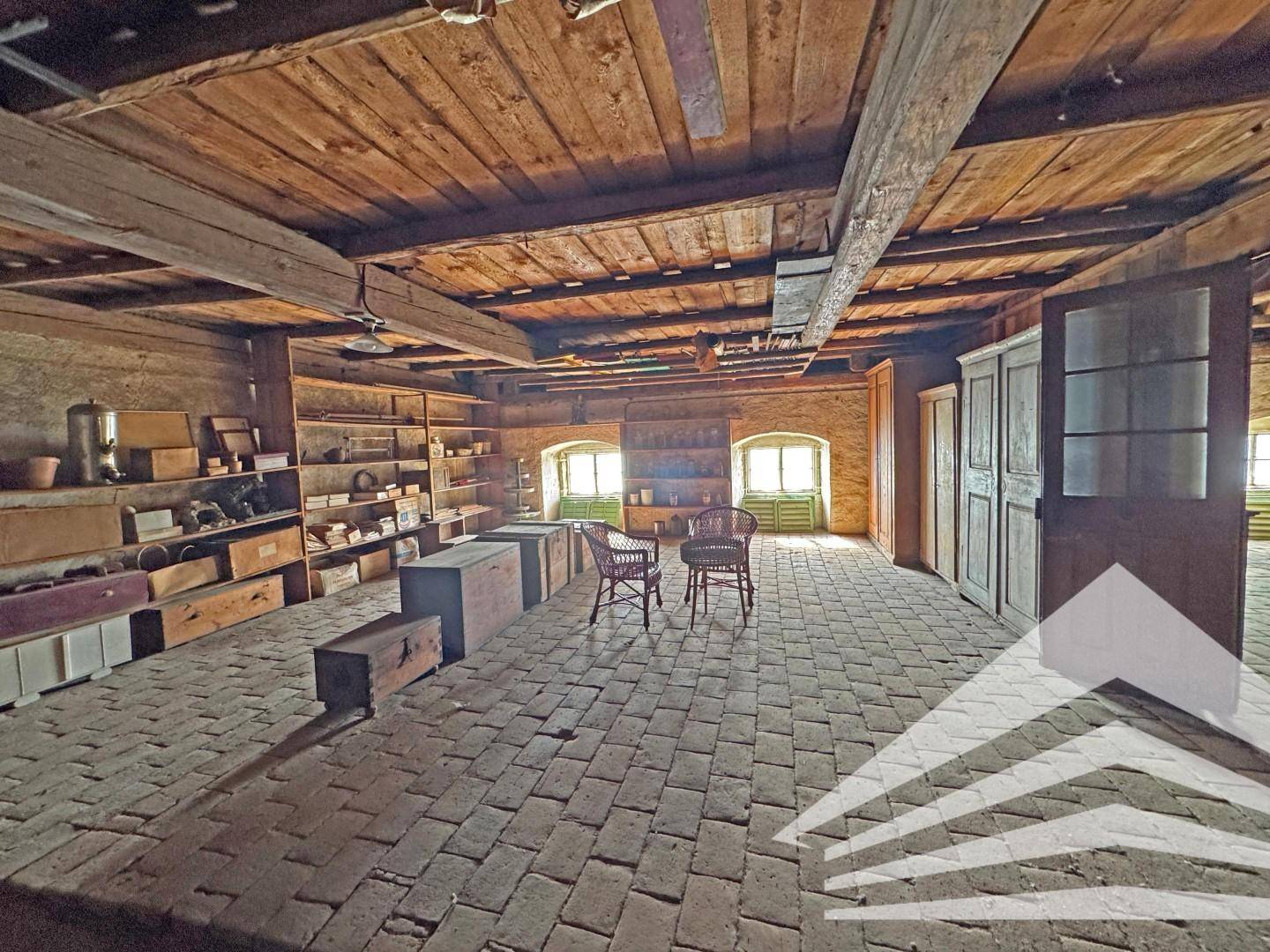 Dachbodenbereich mit Holzdecke, Regalen und zwei Stühlen, ideal als Lagerraum.