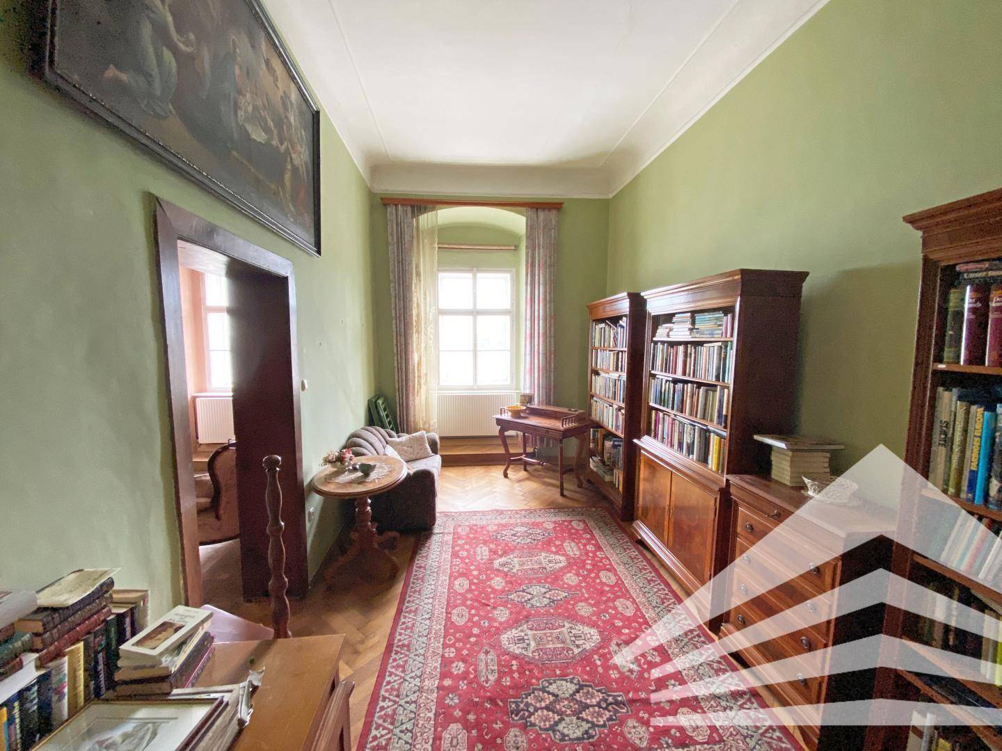 Gemütliche Bibliothek mit Holzbücherregalen, Parkettboden und einem Fenster.