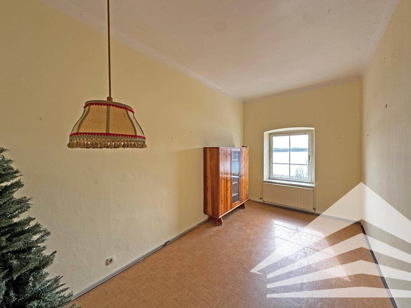 Helles Zimmer mit gelben Wänden, Korkboden und einem Fenster, das Tageslicht hereinlässt.