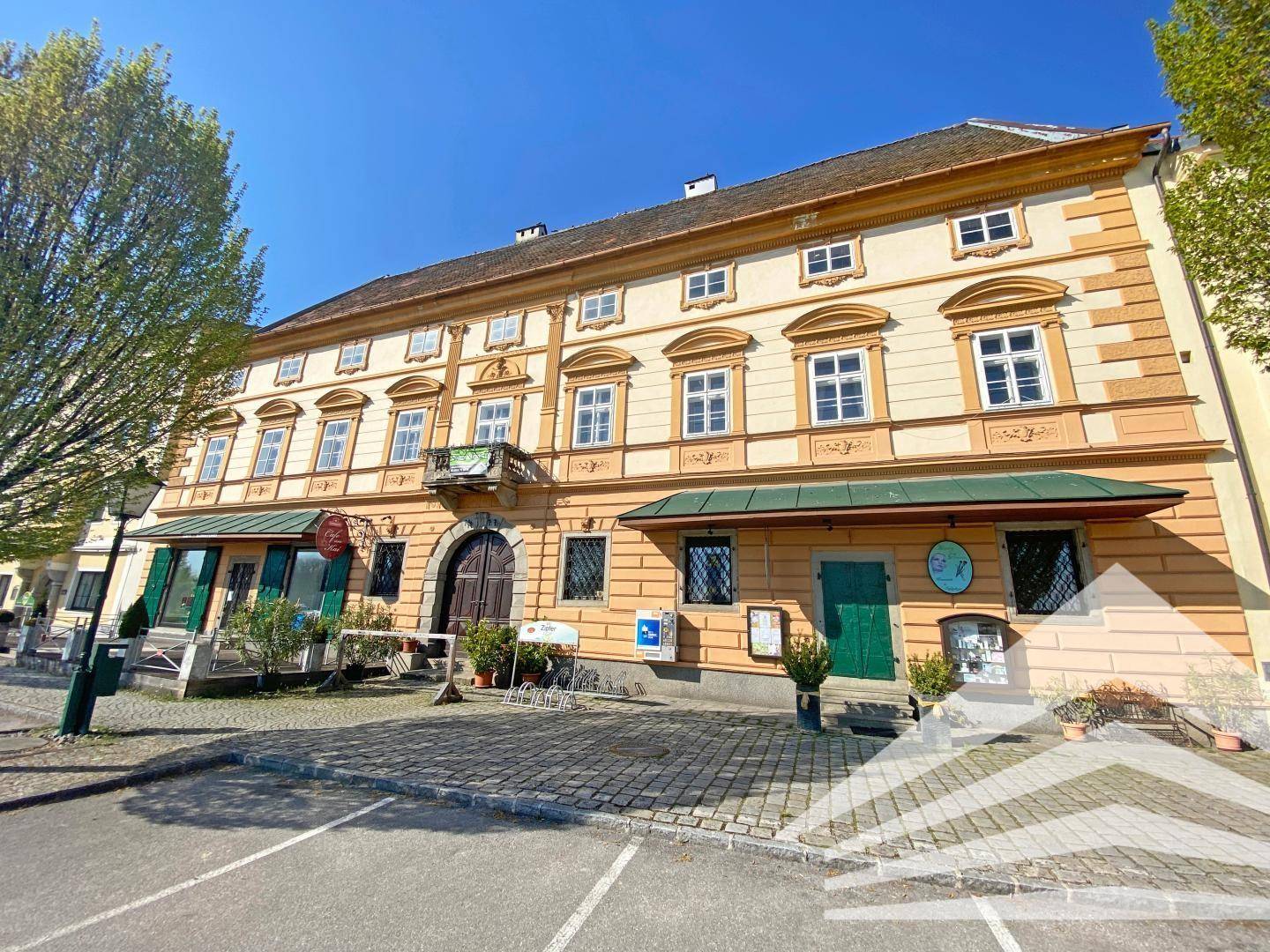 Historisches Gebäude mit oranger Fassade, traditionellen Fenstern und einem kleinen Balkon.