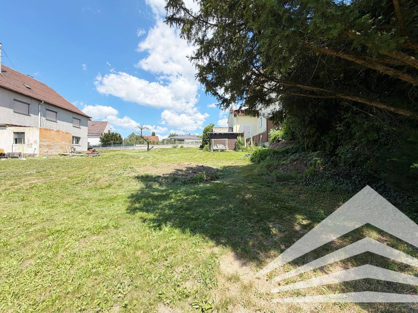 Großes, sonniges Grundstück mit Rasenfläche und Bäumen, umgeben von weiteren Wohnhäusern.