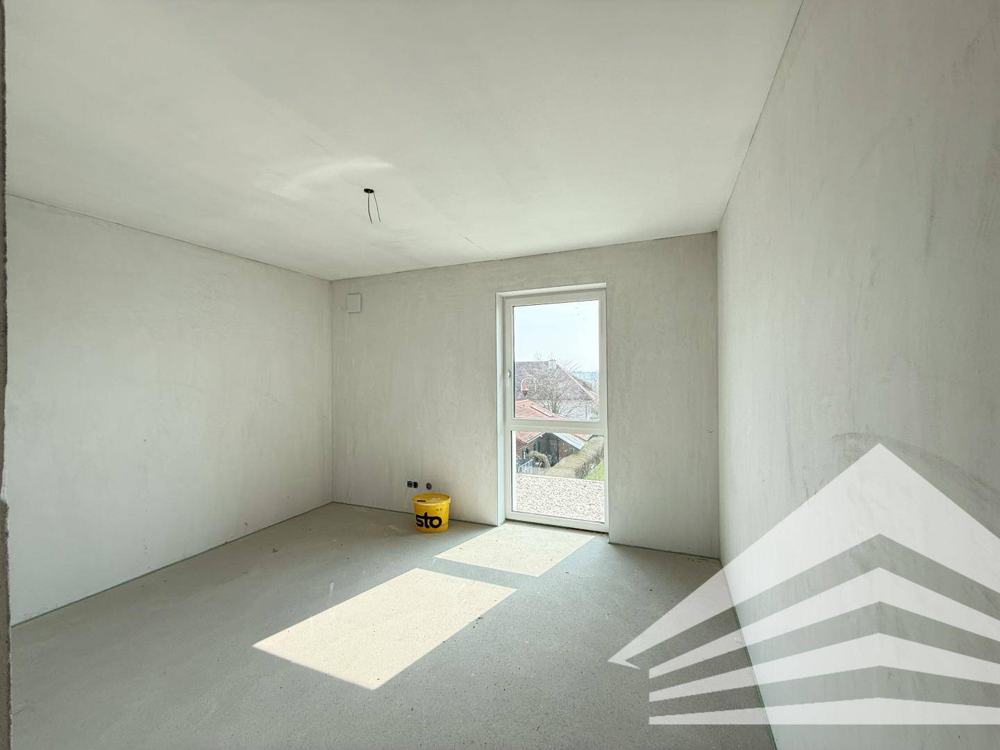 Heller, unfertiger Raum mit Fenster und viel Tageslicht, bereit für den Innenausbau.