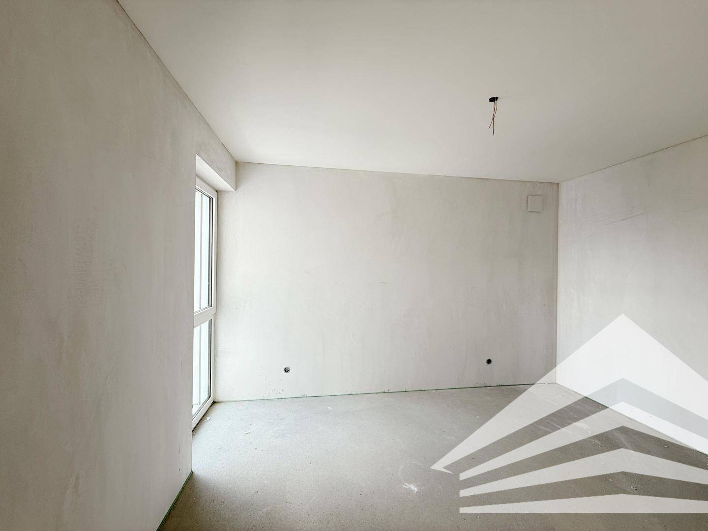 Unfertiges Schlafzimmer mit weiß verputzten Wänden und einem hohen Fenster.