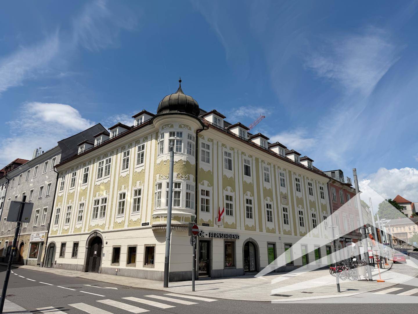 Historisches Eckgebäude mit markanter Kuppel und traditioneller Fassadengestaltung an einer belebten Straße.