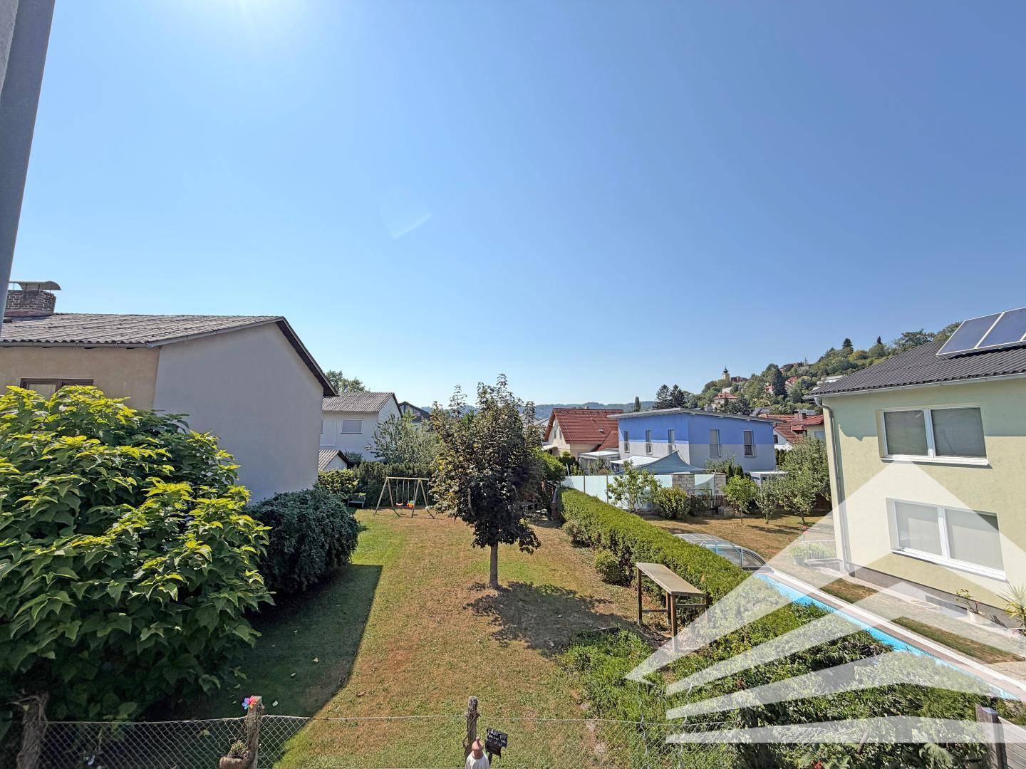 Weitläufiger Blick über einen grünen Garten und die umliegende Wohngegend.
