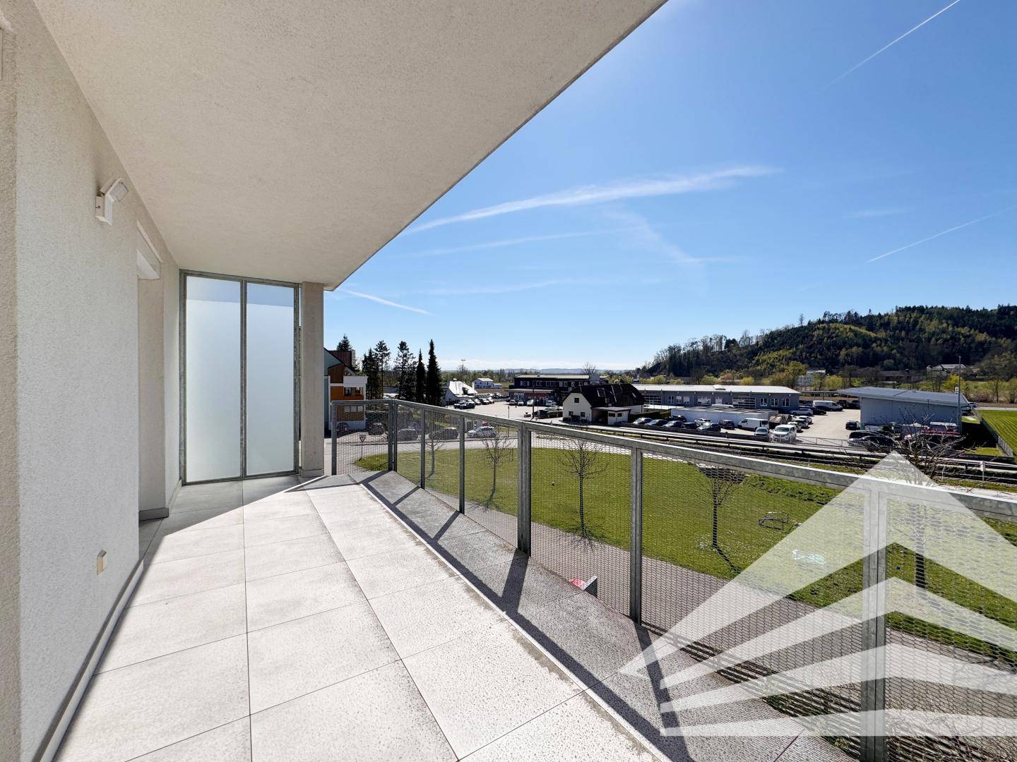 Heller Balkon mit Fliesenboden und Blick auf die Umgebung, ideal für entspannte Stunden im Freien.